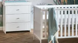 A bright baby's room showcasing a crib and dresser, creating a safe and inviting space for infants.